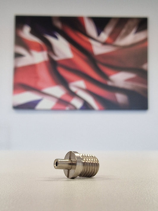 Metallic TECNI cable Gripper on a white table with a blurred union jack background 170.012.002