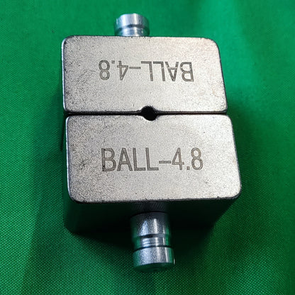 Photo of a ball die set put together showing the gab and top and bottom fitted together. Showing engraving marks on green background. 