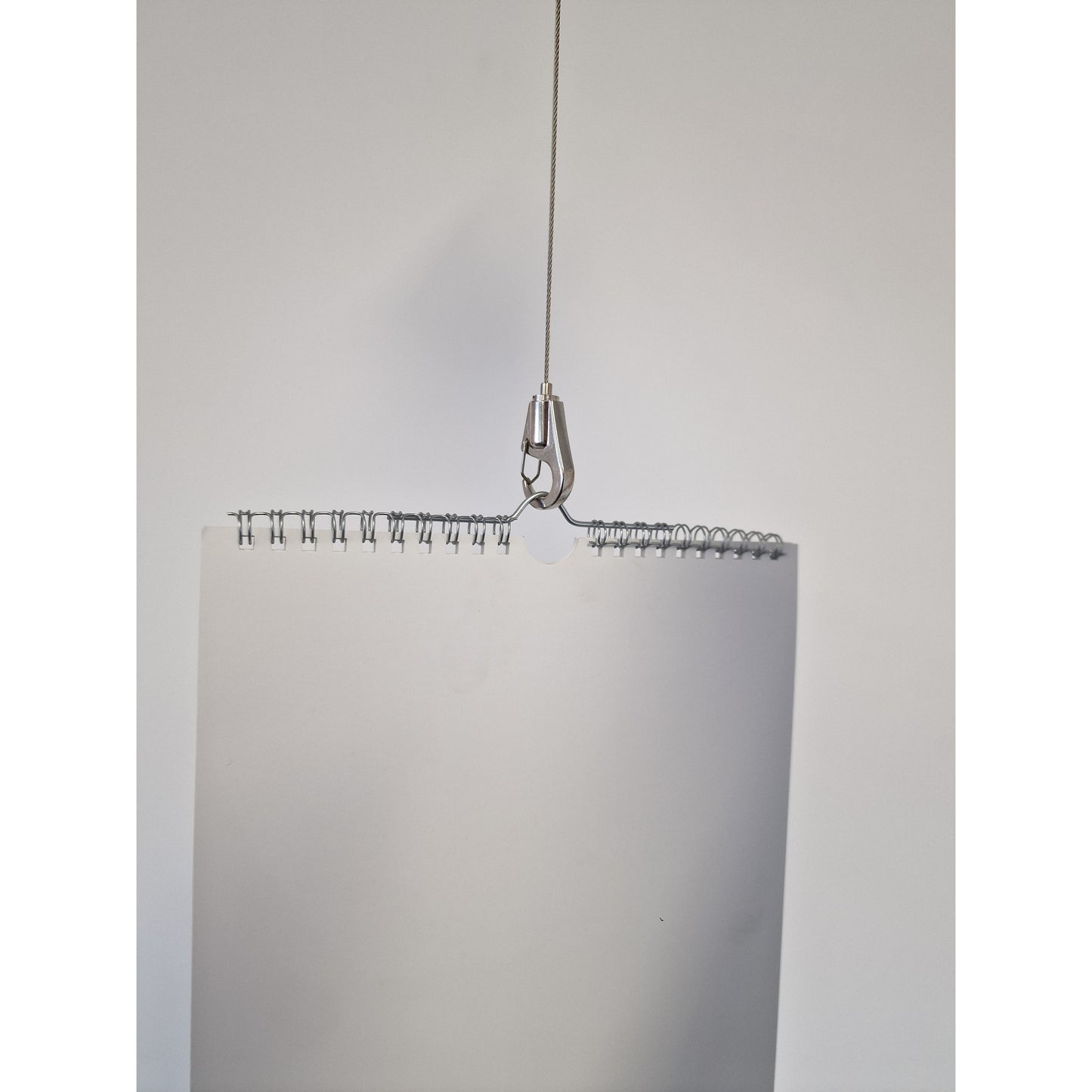 Metallic Hook Gripper on wire rope holding a calendar on a white background