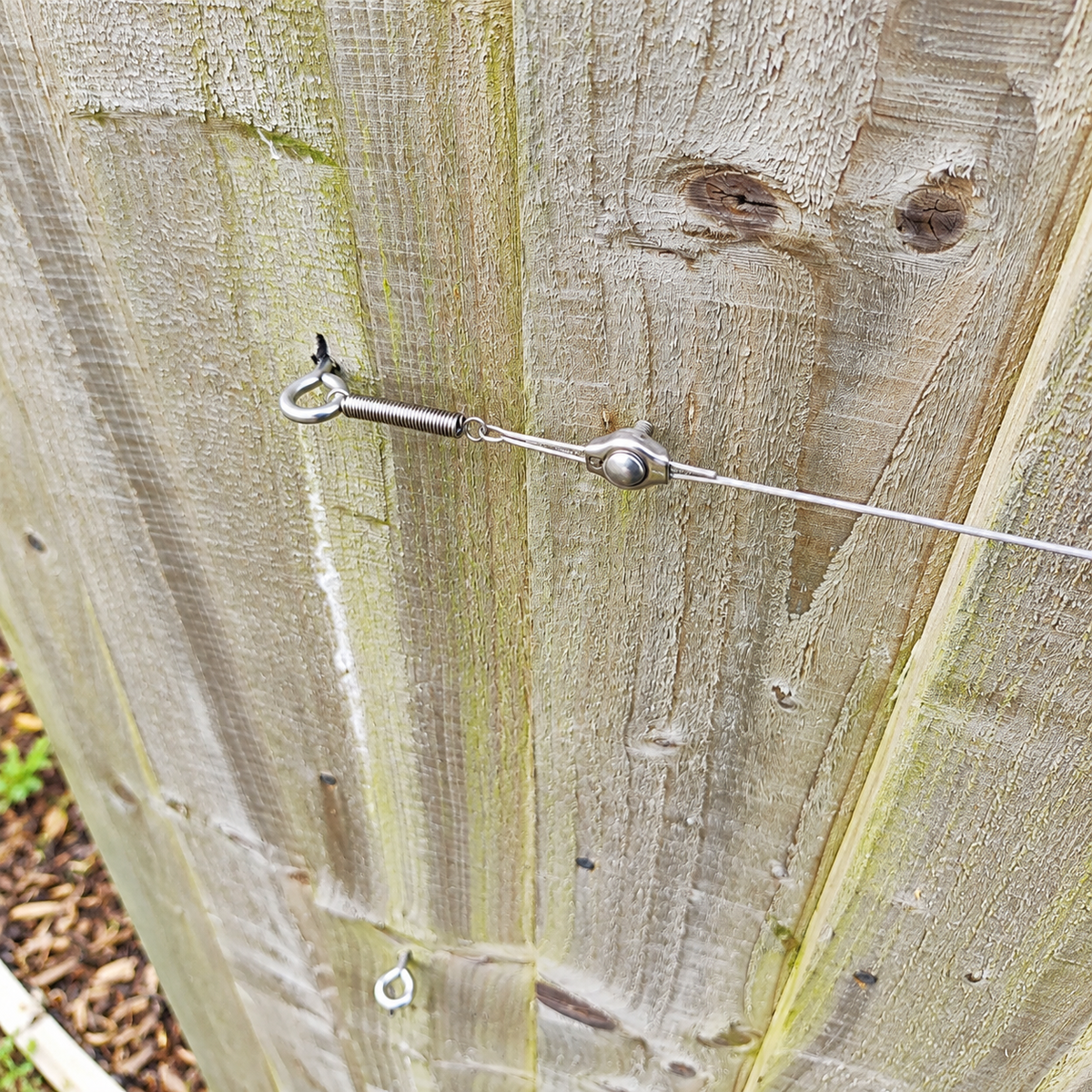 Photo of a cable tensioner on weathered fence showing how it is all assembled together. 