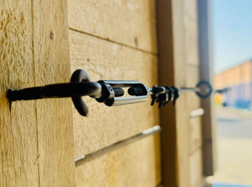 Close-up of TECNI BLACK Trellis system on a wooden fence with blurred background
